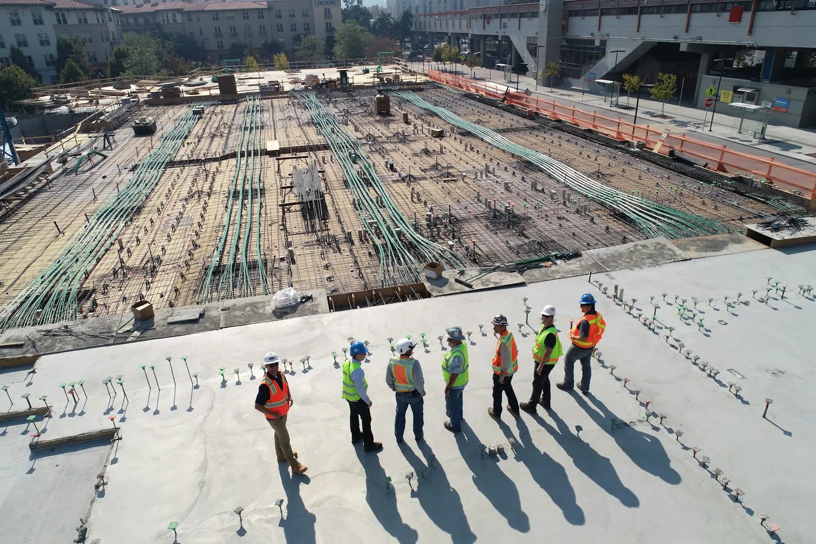 Engineers and construction crews surveying a large reinforced-concrete worksite.